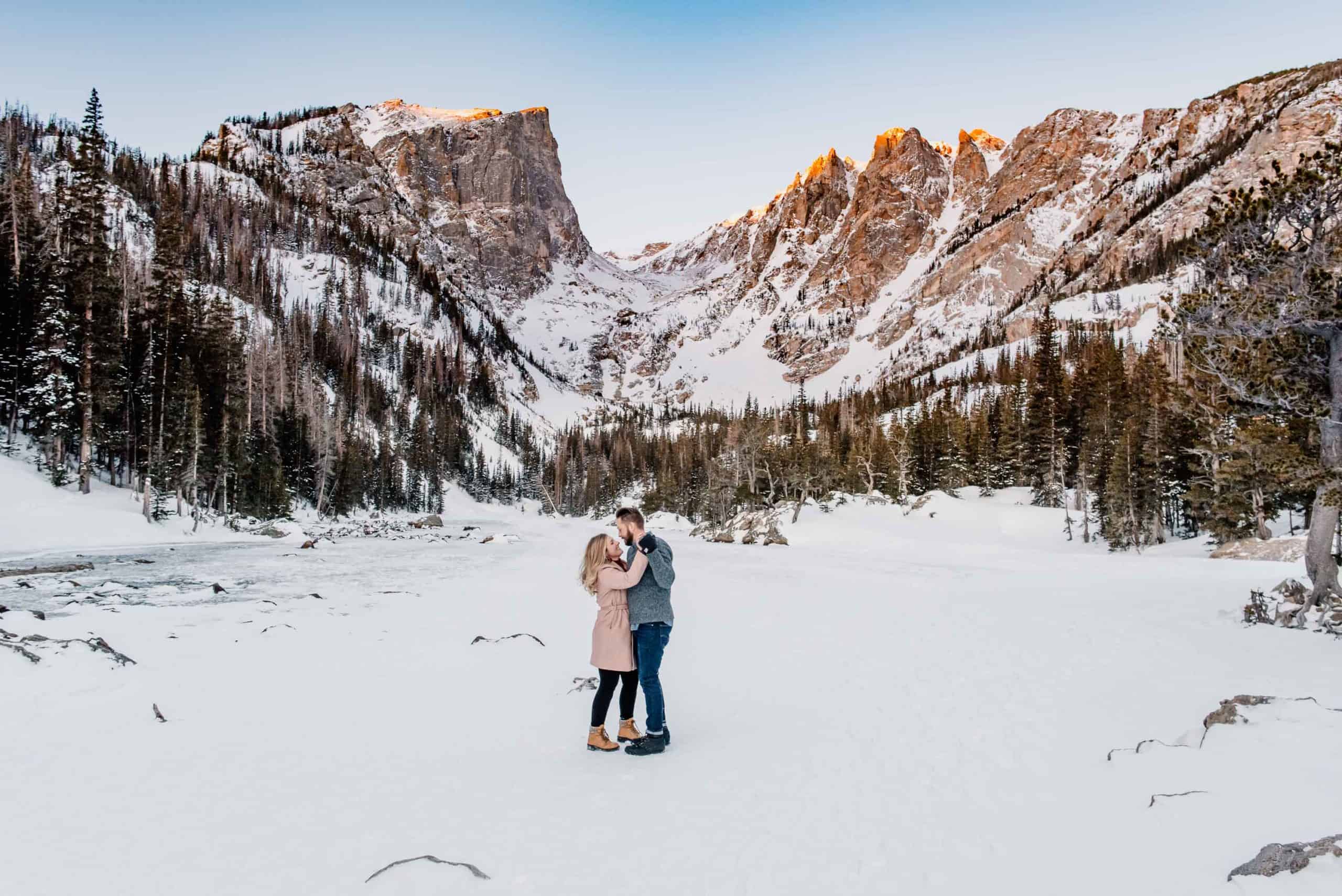 couple who followed this simple proposal ideas list and denver proposal ideas list to have a proposal photographed by Celebrate Again in the mountain of Colorado as the couple dances and the sun illuminates the sky above the peaks of this frozen over alpine lake