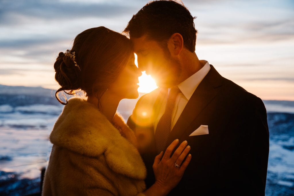bride and groom snuggling close as the sun burst between their faces