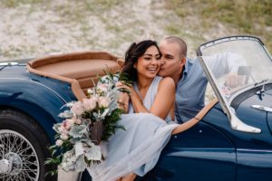 couple in a vintage car on a beach near charleston having a romantic time together.