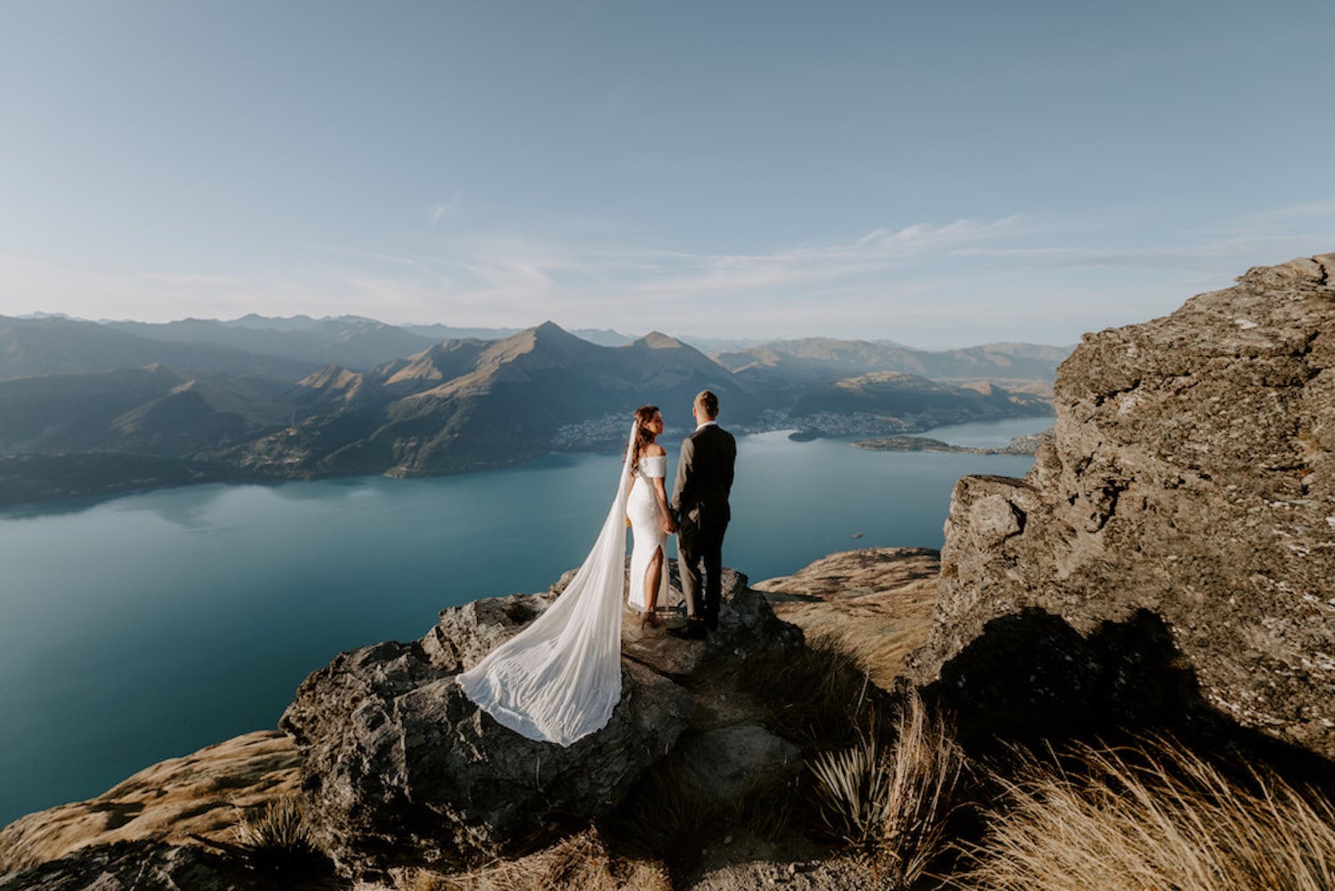 wedding couple standing on a rock over looking an alpine lake