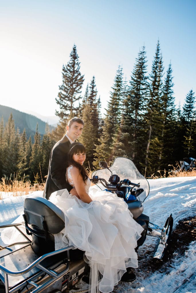 Eloping couple getting married by driving on a snowmobile to a remote location in Colorado