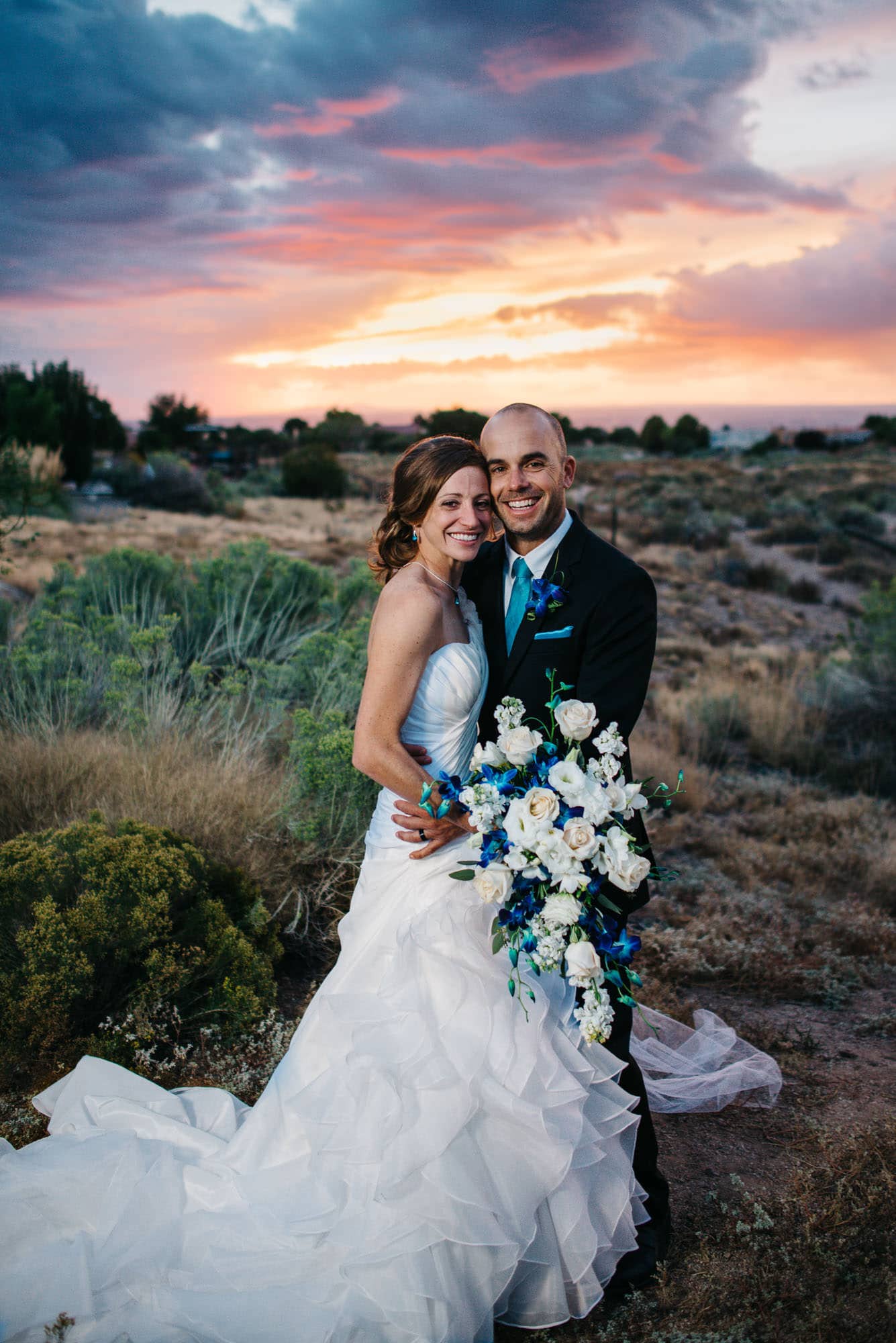 bride and groom smiling at camera during an epic sunset