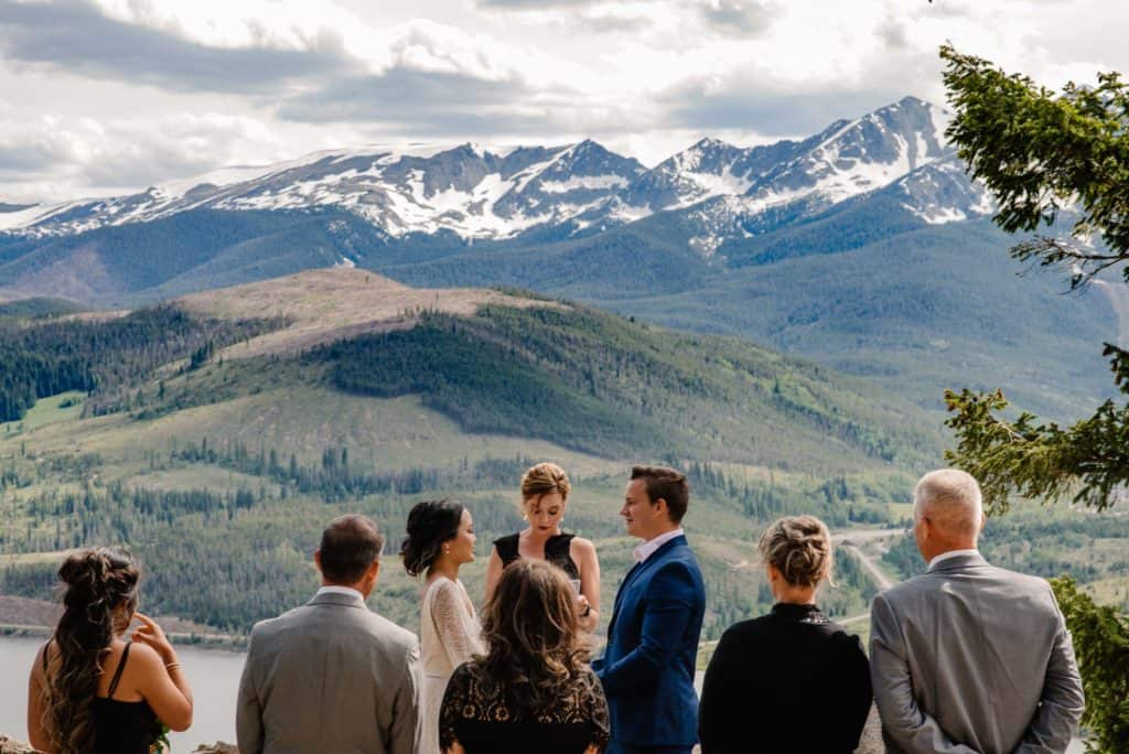small Breckenridge elopement location at sapphire point guests standing around bride and groom overlooking the mountains into Breckenridge.