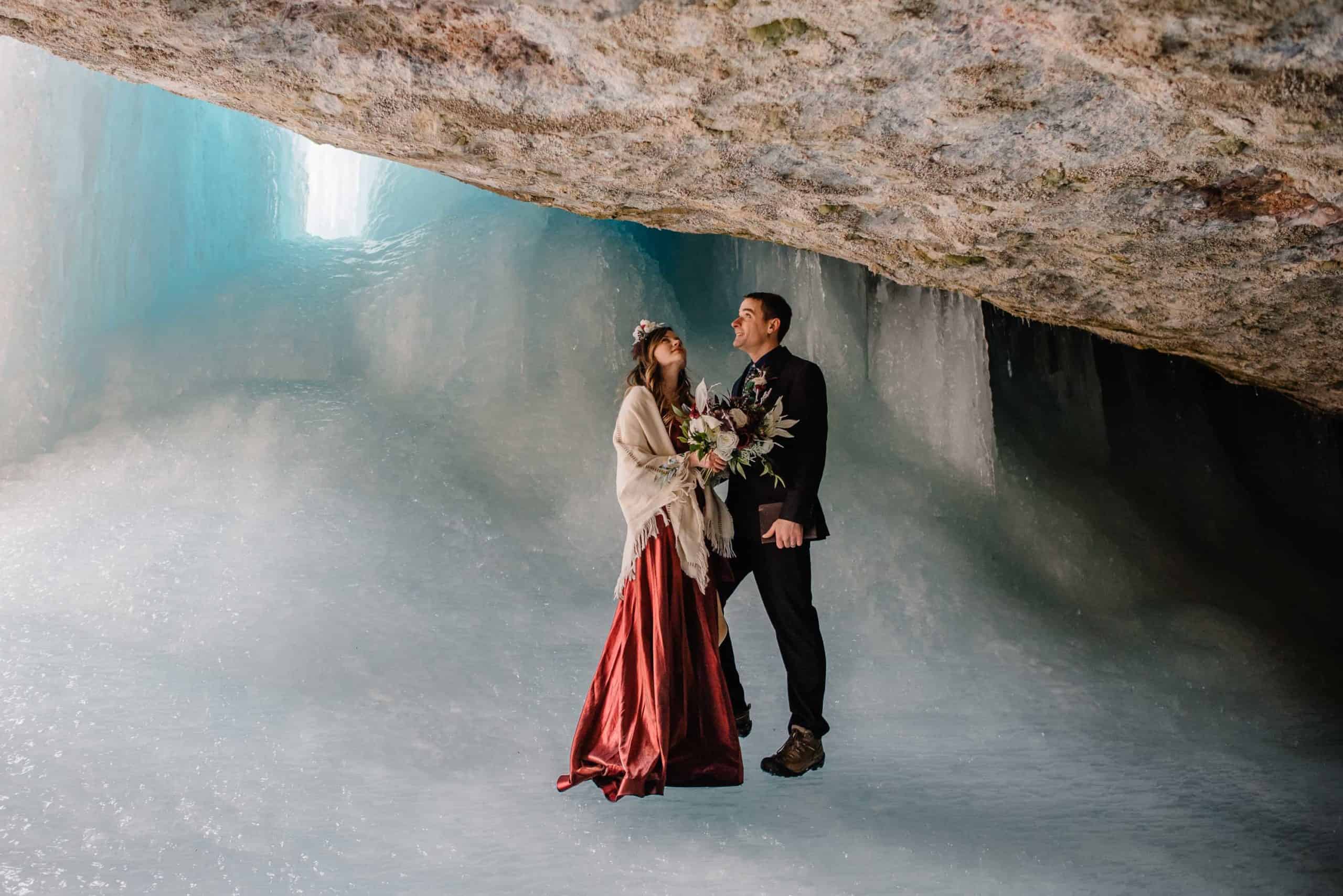 couple standing in an ice cave staring up at the majesty of the place