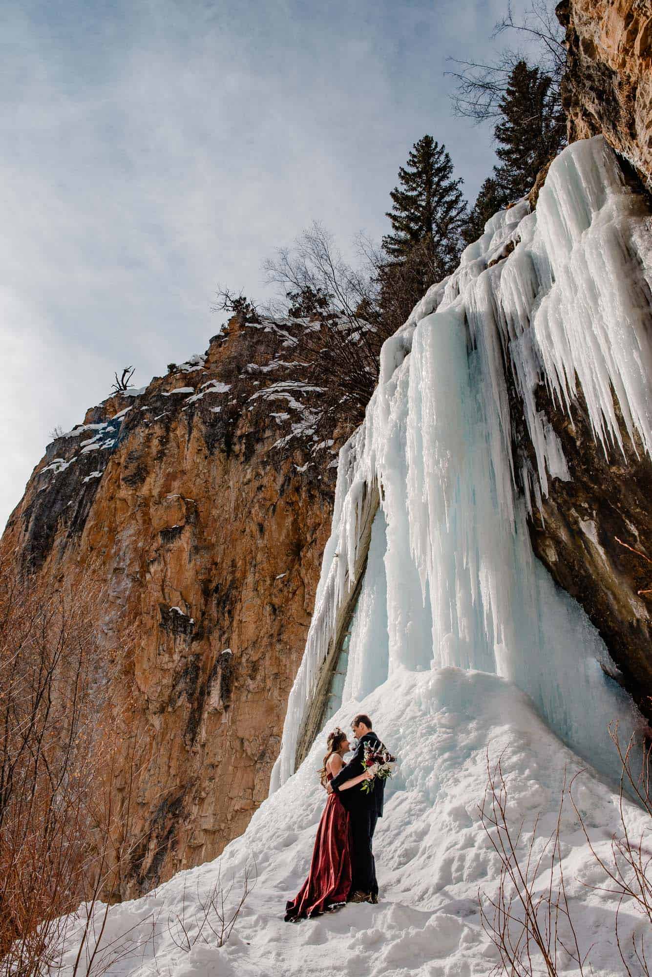 Bride and groom standing near waterfalls as they elope in Colorado