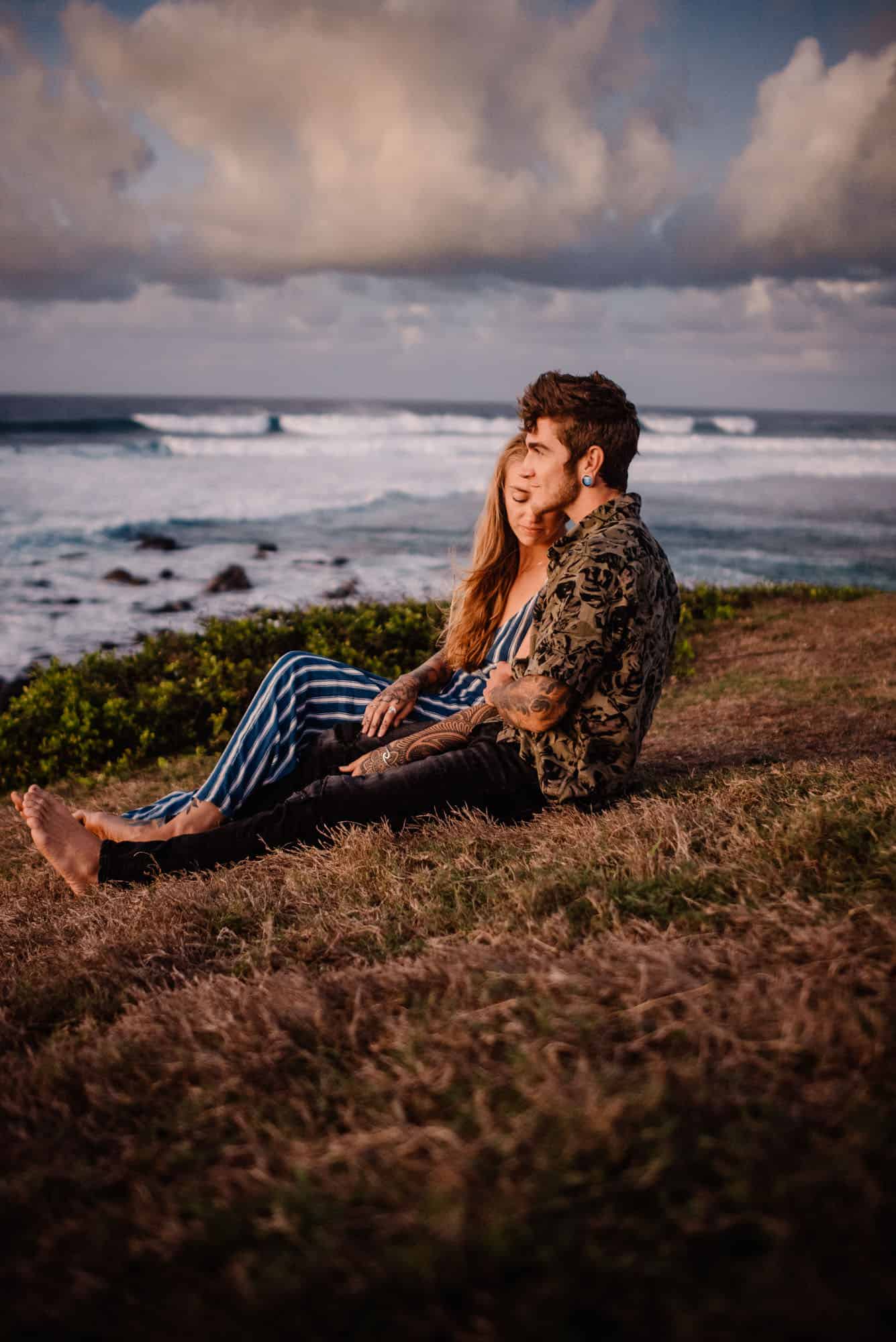 couple snuggling on beach grassy field enjoying snuggles as they do the romantic things to do in maui