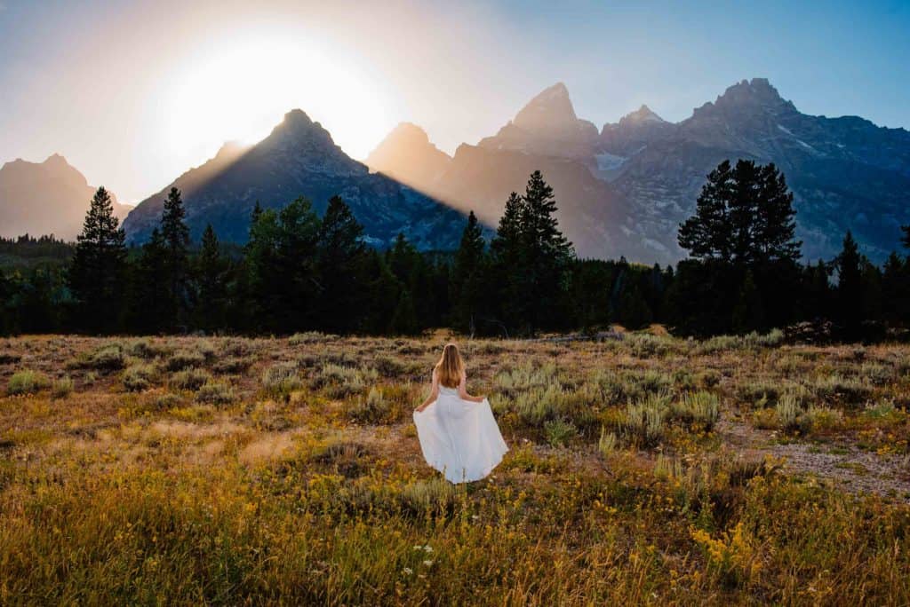 bride walking towards mountain as sunsets. She's happy that she is eloping during the pandemic