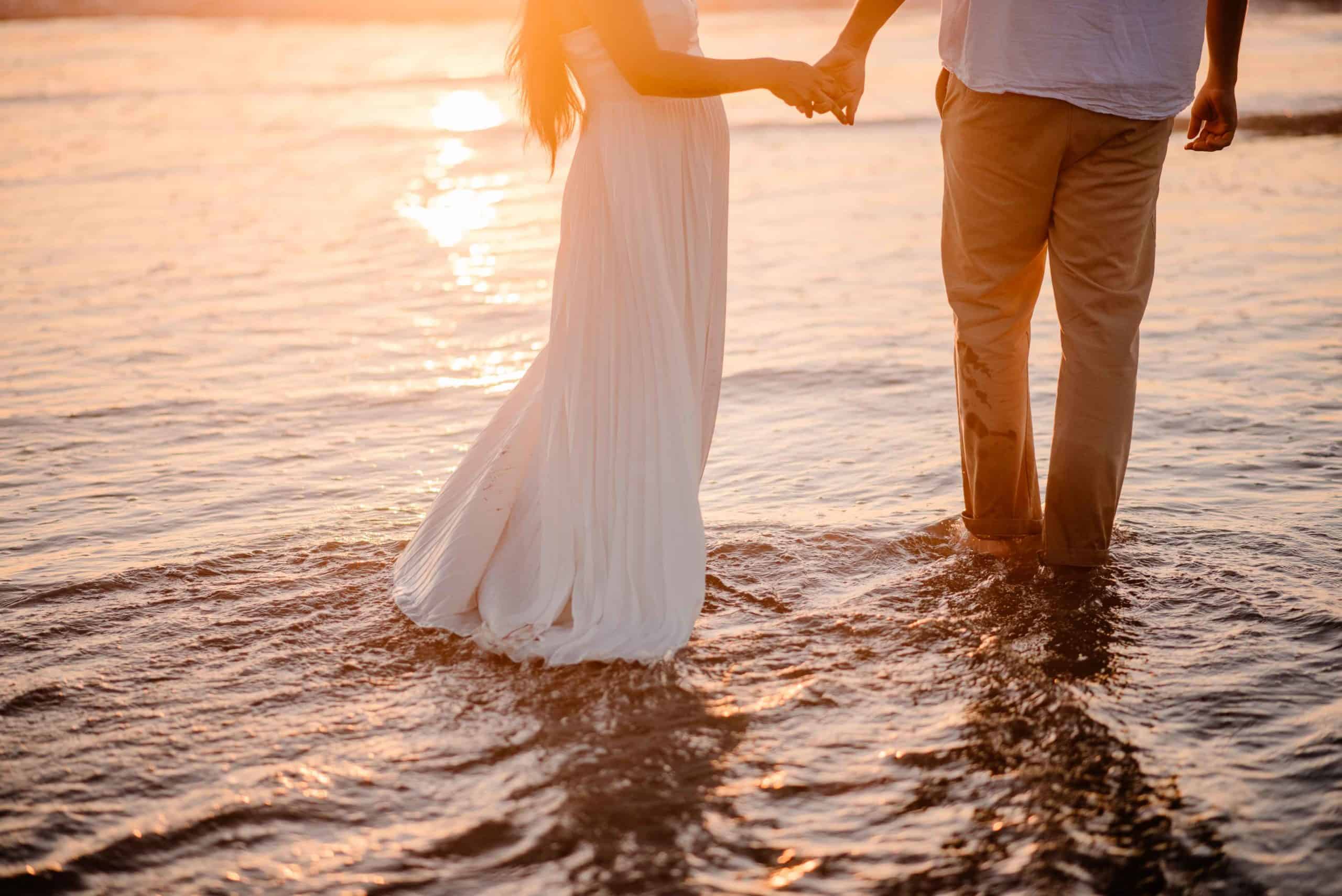 couple holding hands walking into the sunset