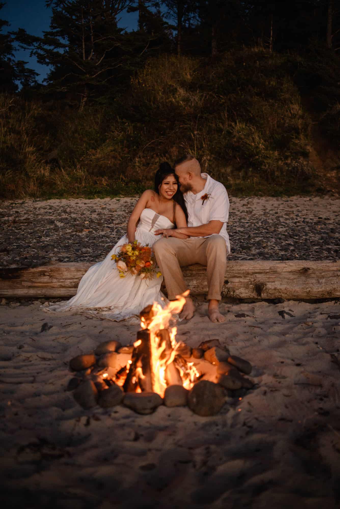 how to celebrate new year couple sitting around a beach side fire