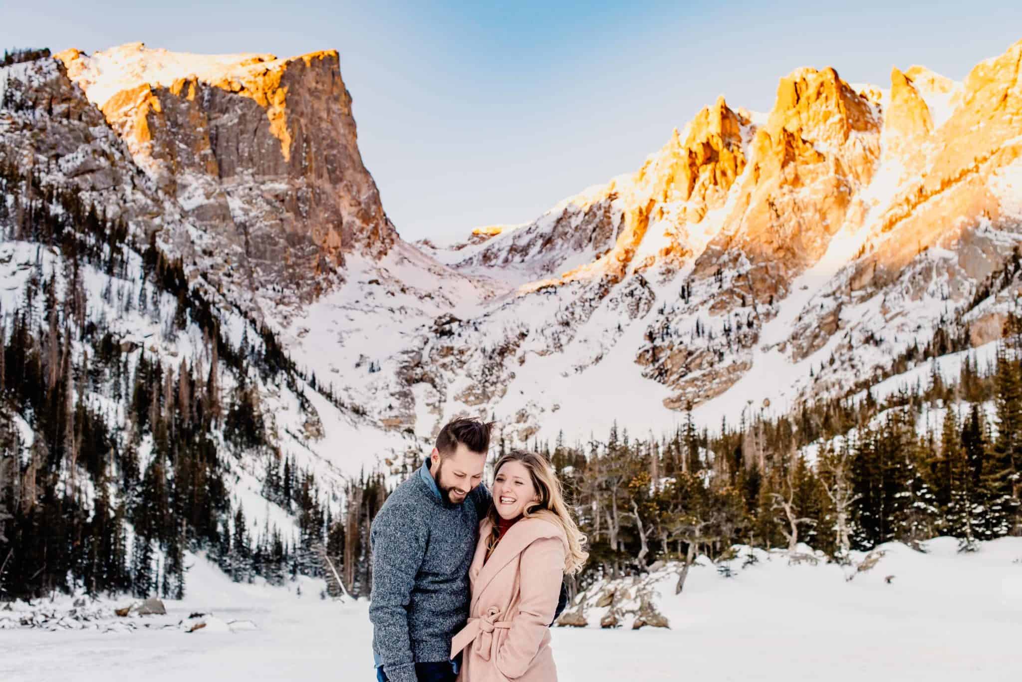 couple at a mountain in winter as the sun rises and illuminates the mountains