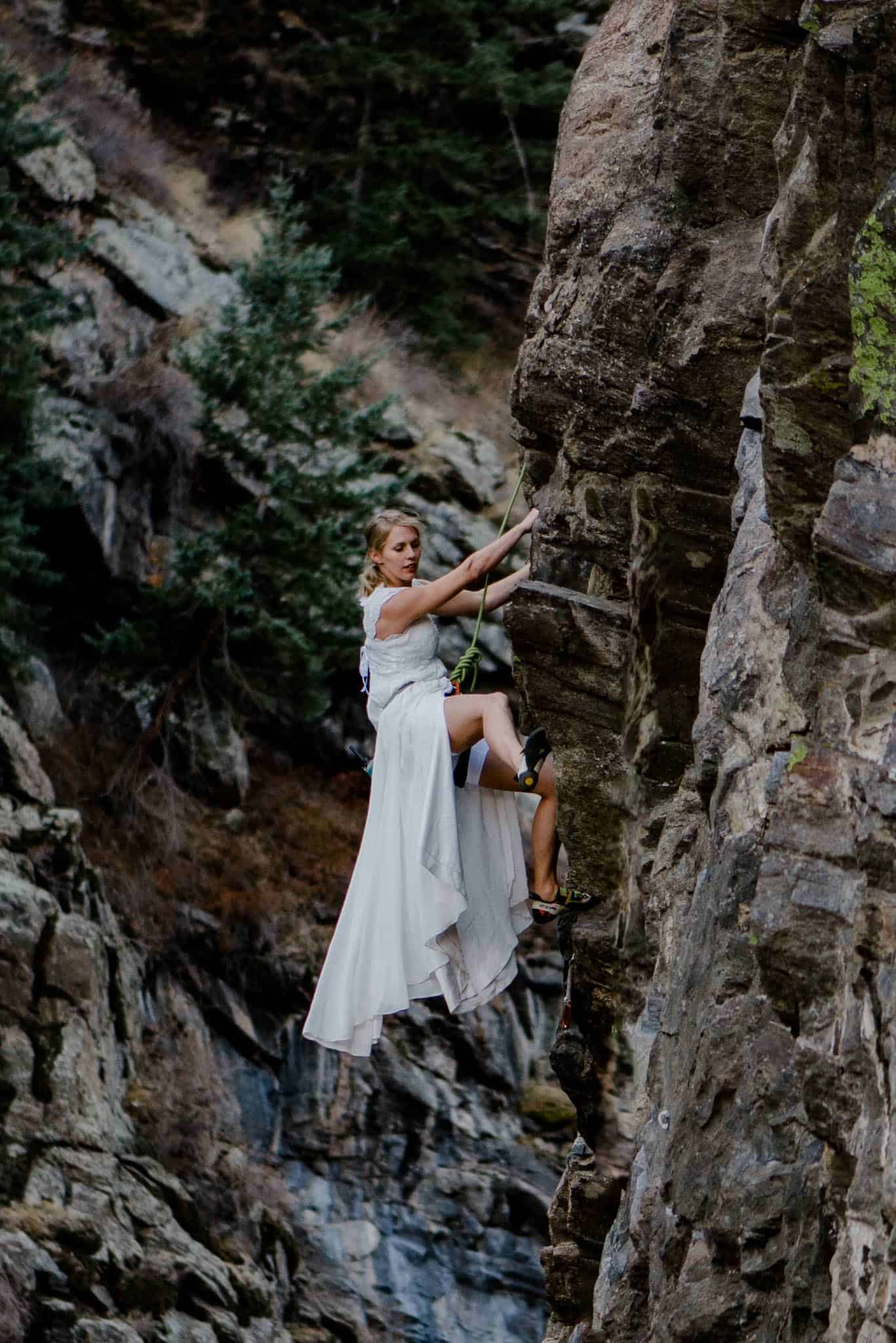 female rock climbing in her wedding dress