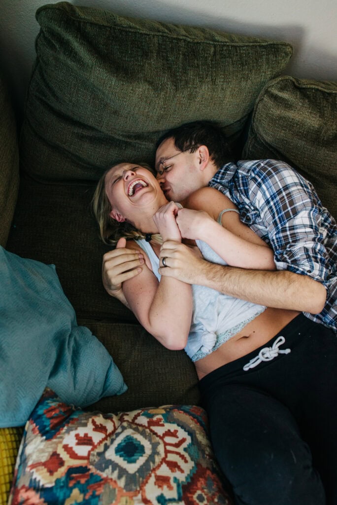 couple laughing during a romantic snuggle attack on the couch