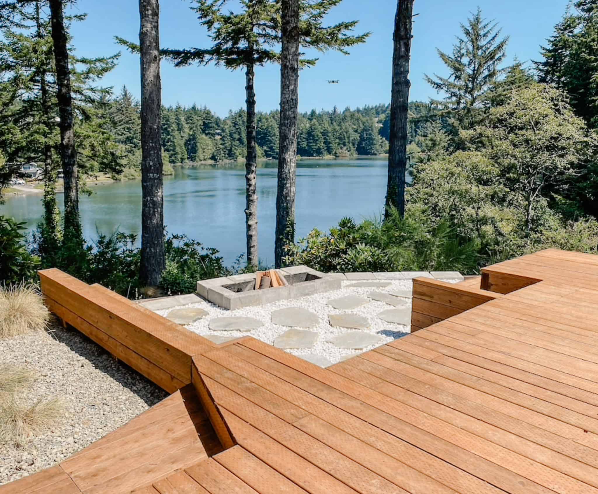 wooden neck stepping down to a stone fire pit on a lake edge
