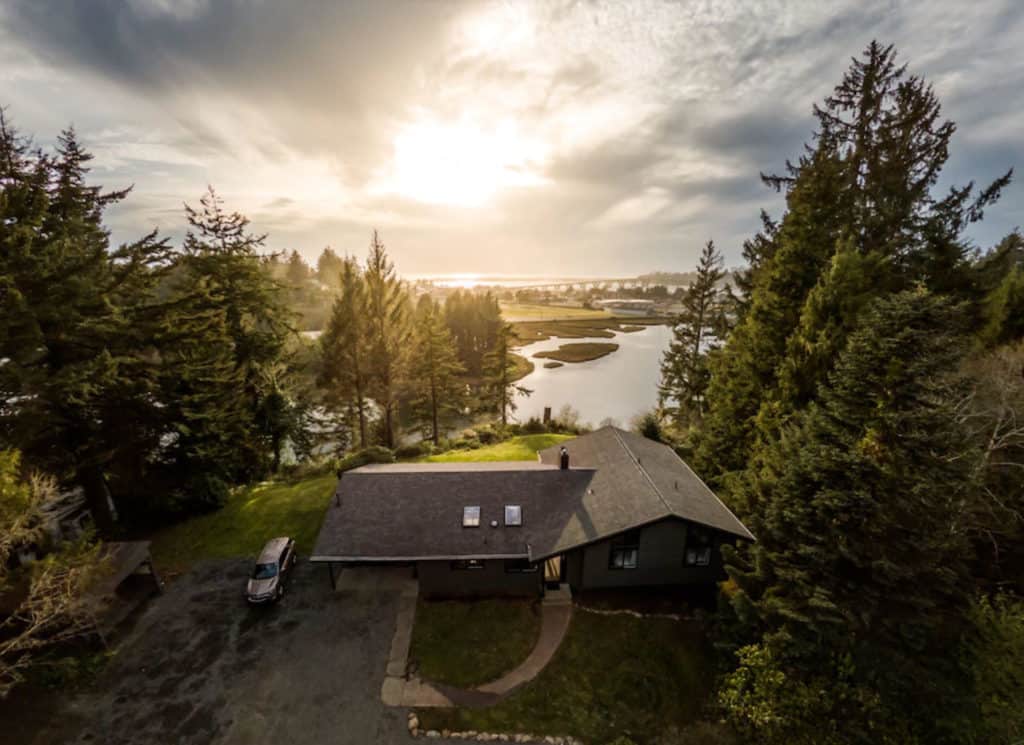 aerial view of an airbnb wedding venue home with a lake and trees in the background