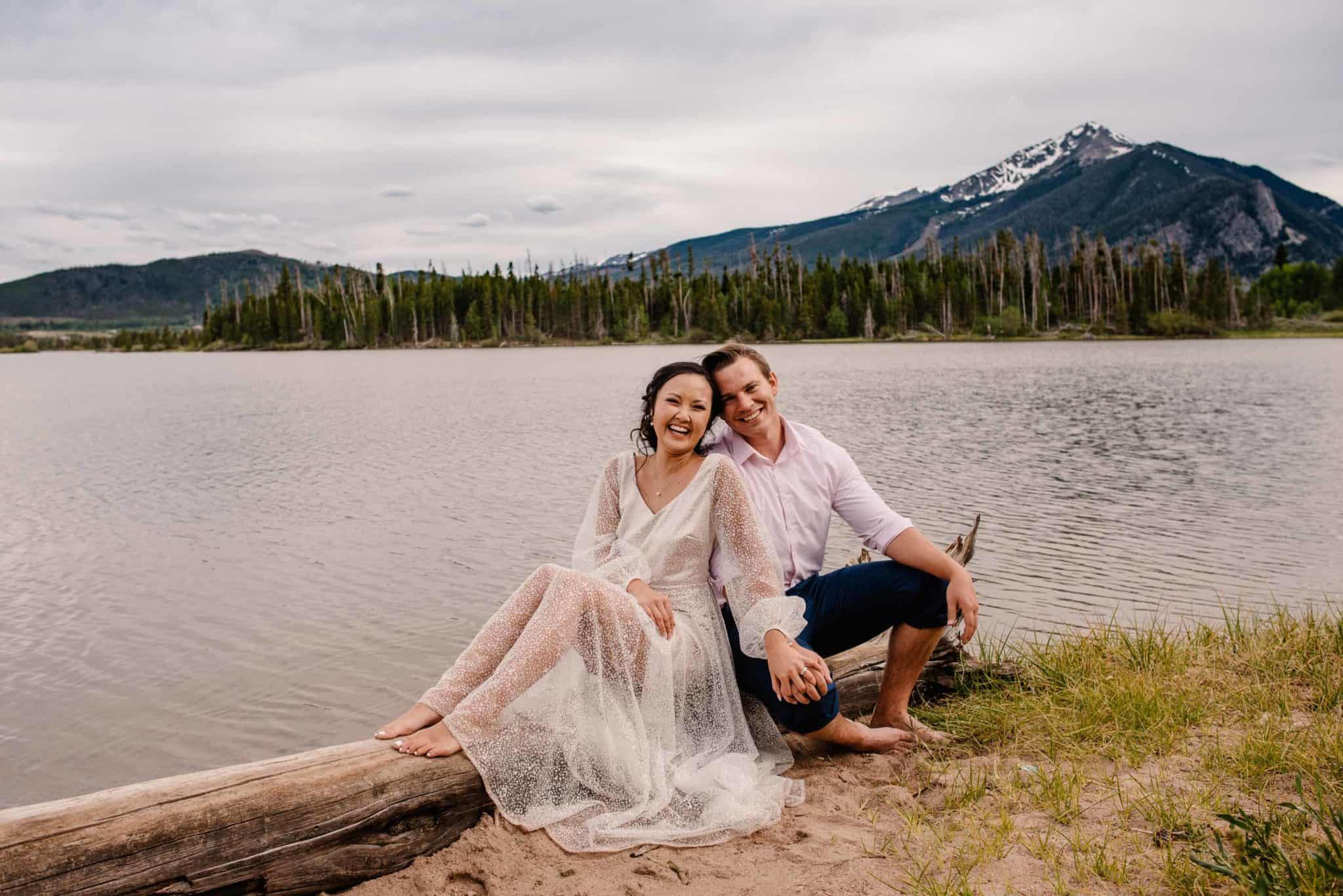 Couple sitting my edge of a lake embracing their unique and special elopement day in the Colorado mountains