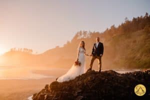 bride and groom on cliff edge with light shinning behind them