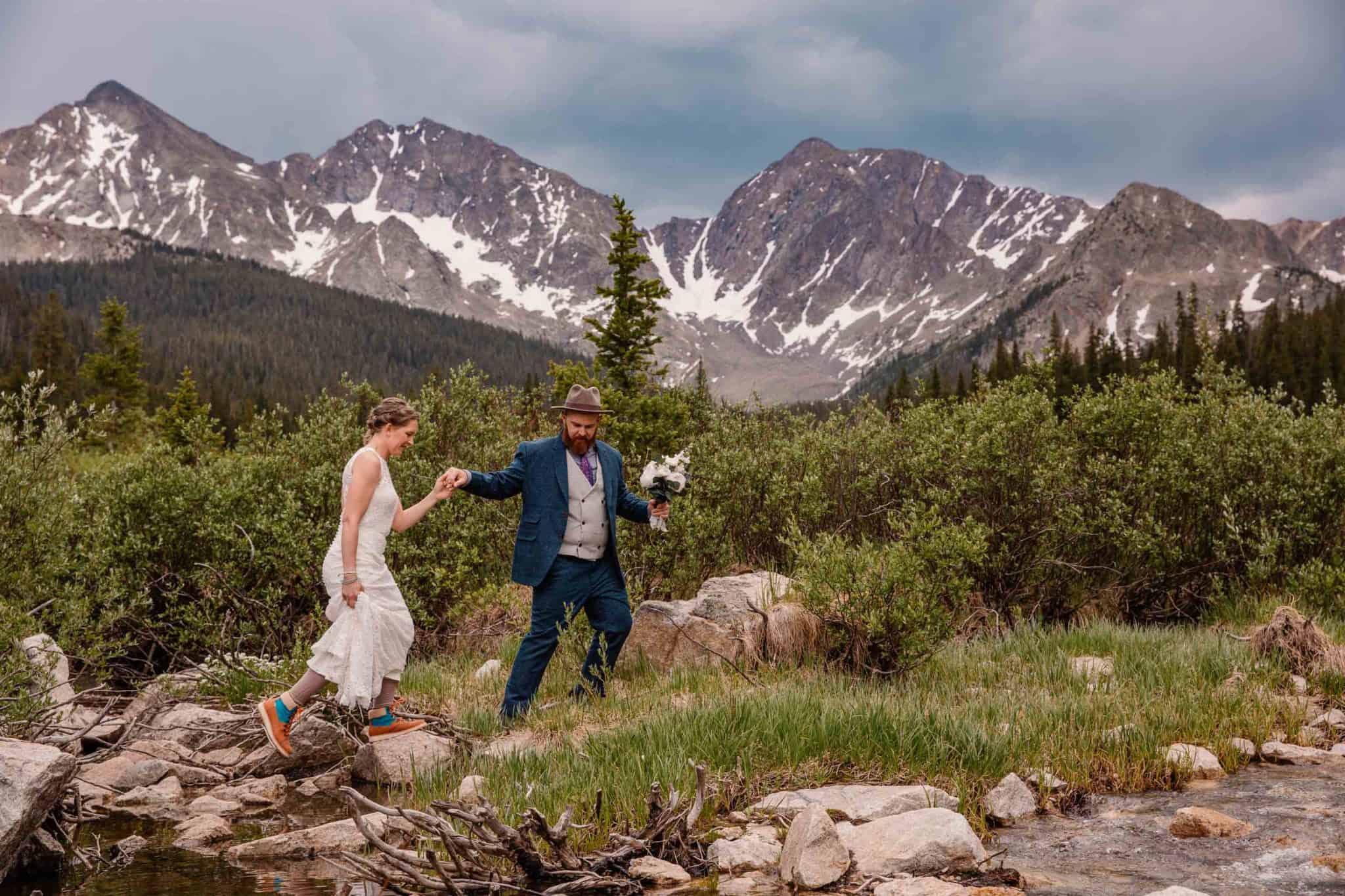 oregon elopement photographer taking photo of couple walking up a rock with the mountains behind them