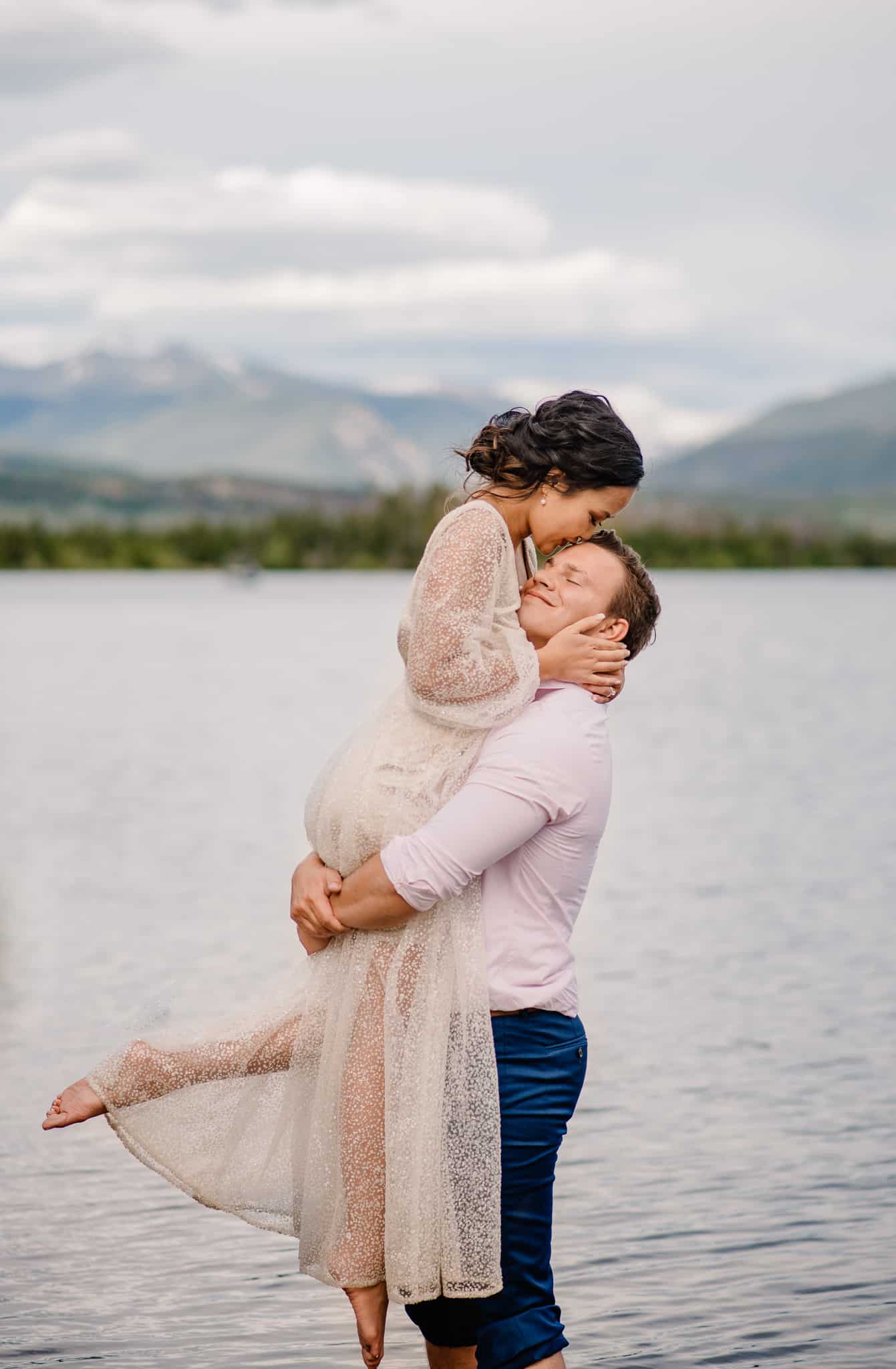 bride being lifted up by groom in alpine lake