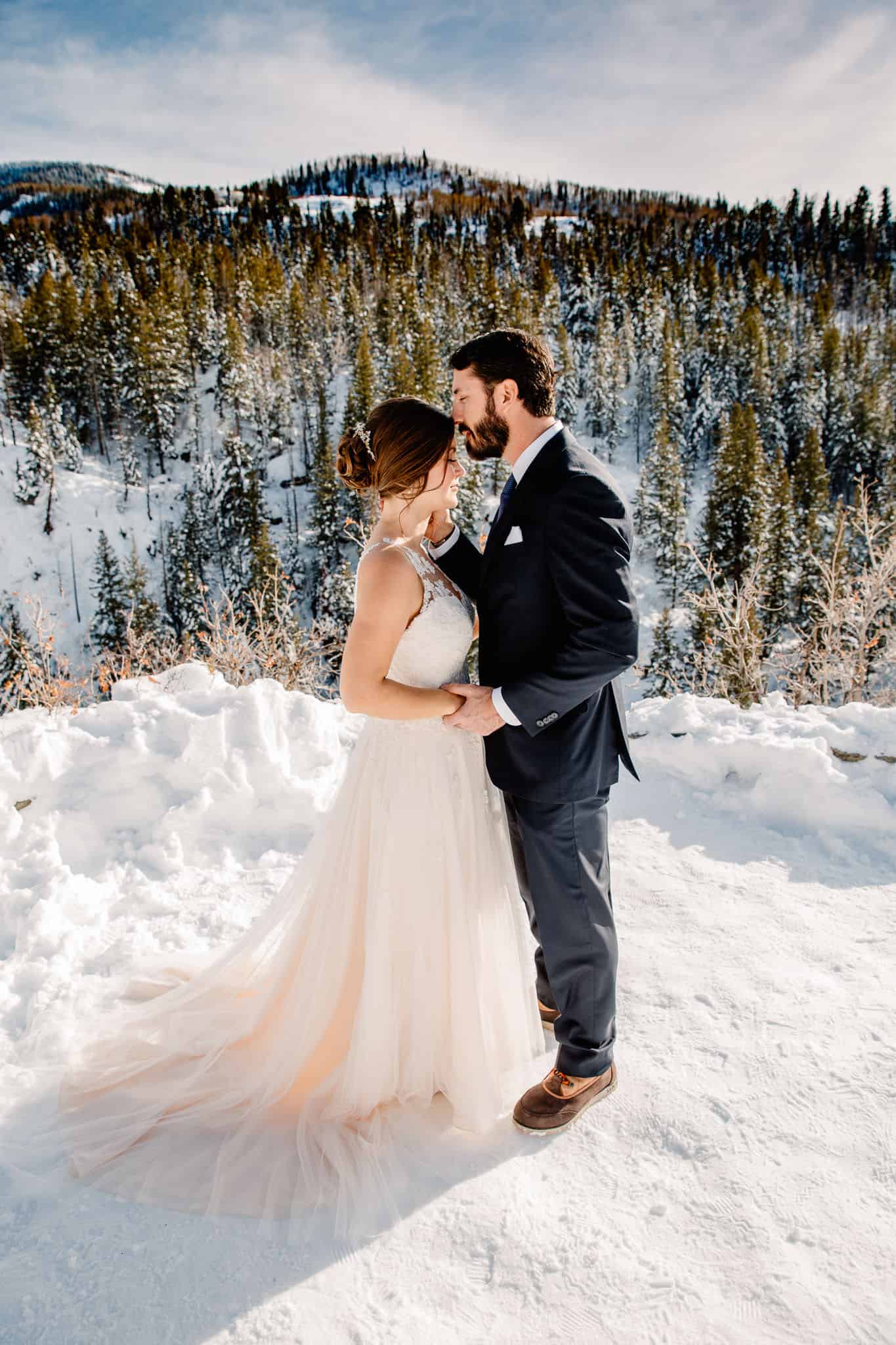 groom kissing bride forehead in the middle of the Oregon mountains in winter