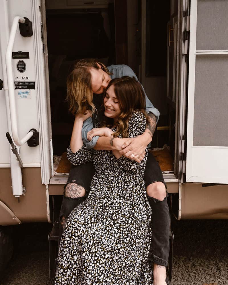Two Oregon elopement photographers snuggled up in the door of their RV