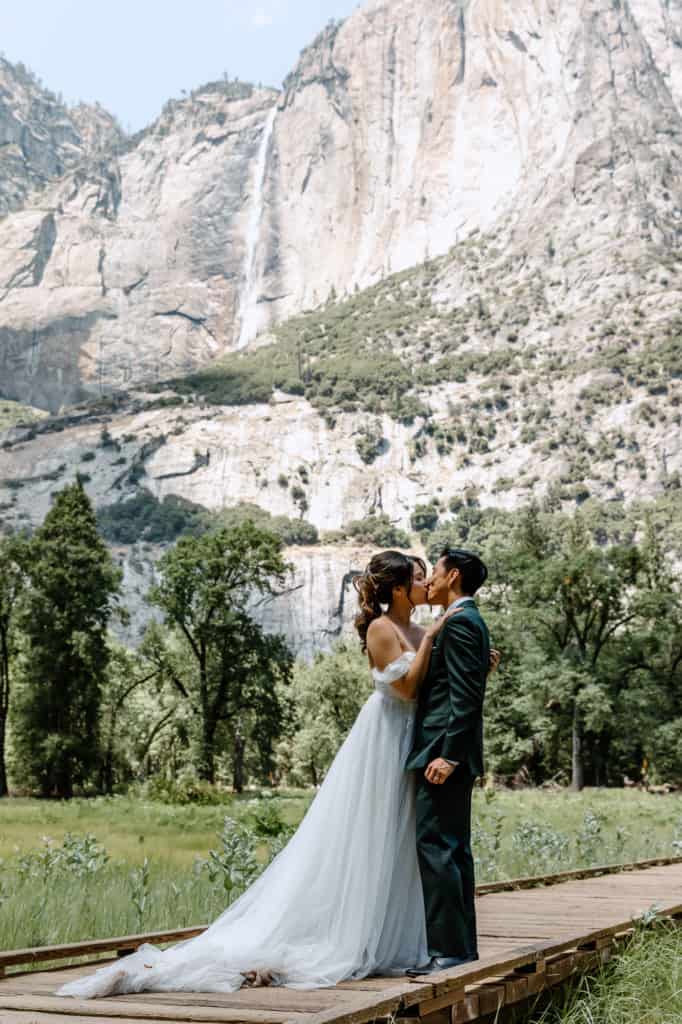 couple standing in Yosemite meadows a waterfall wedding venue in California photo by BH Picture CO