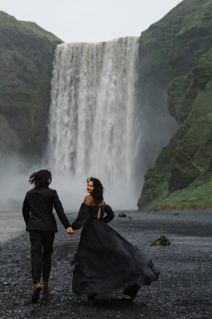 couple walking away from a waterfall photo by Diamond Elopements