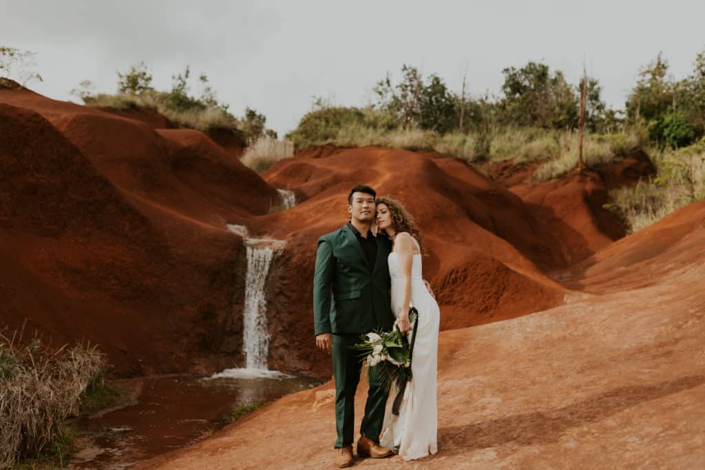 couple standing in front of Red Dirt Falls in Kauai a good waterfall wedding venue photo by Briana Parks Photography