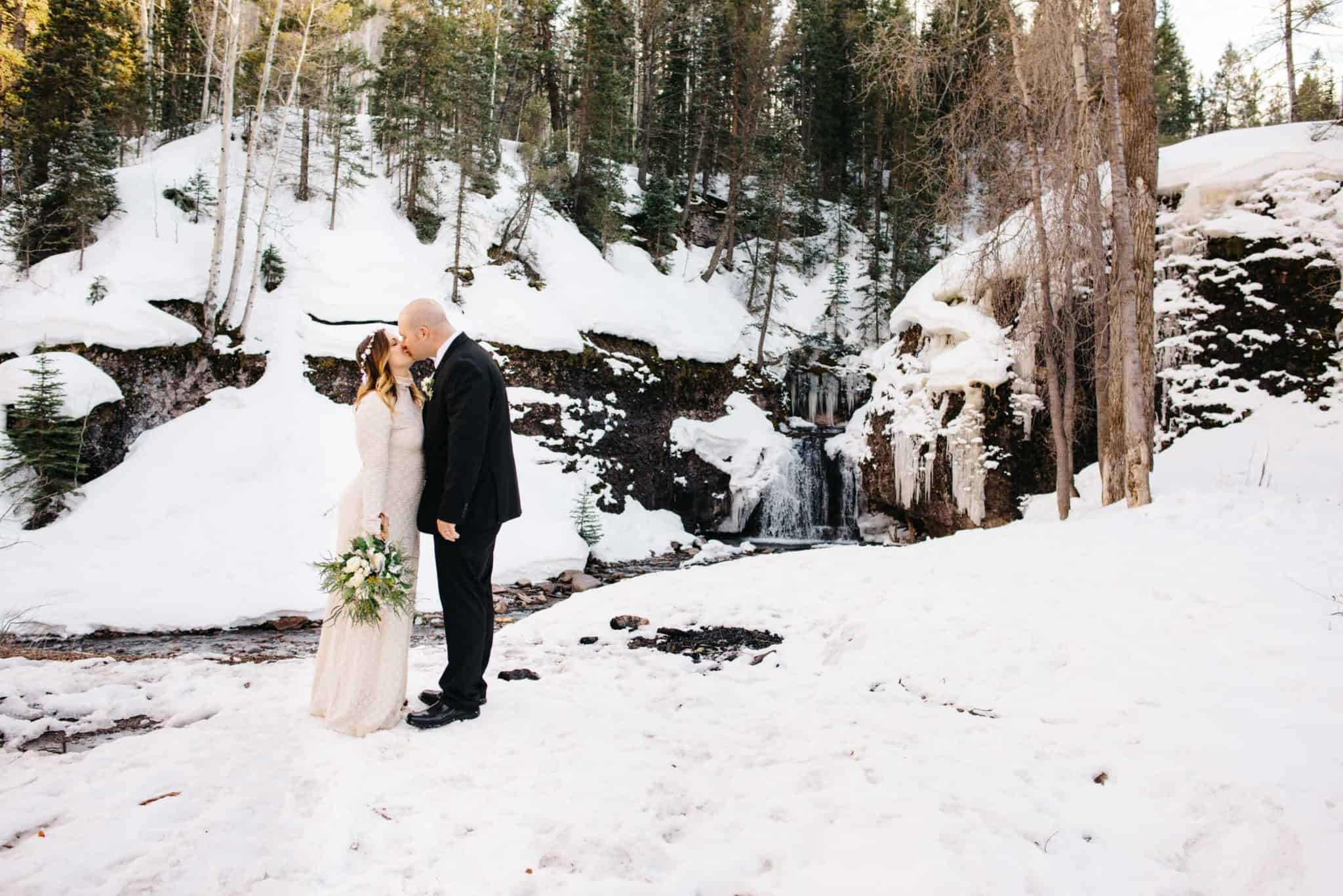 couple in front of frozen waterfall wedding venue in Telluride