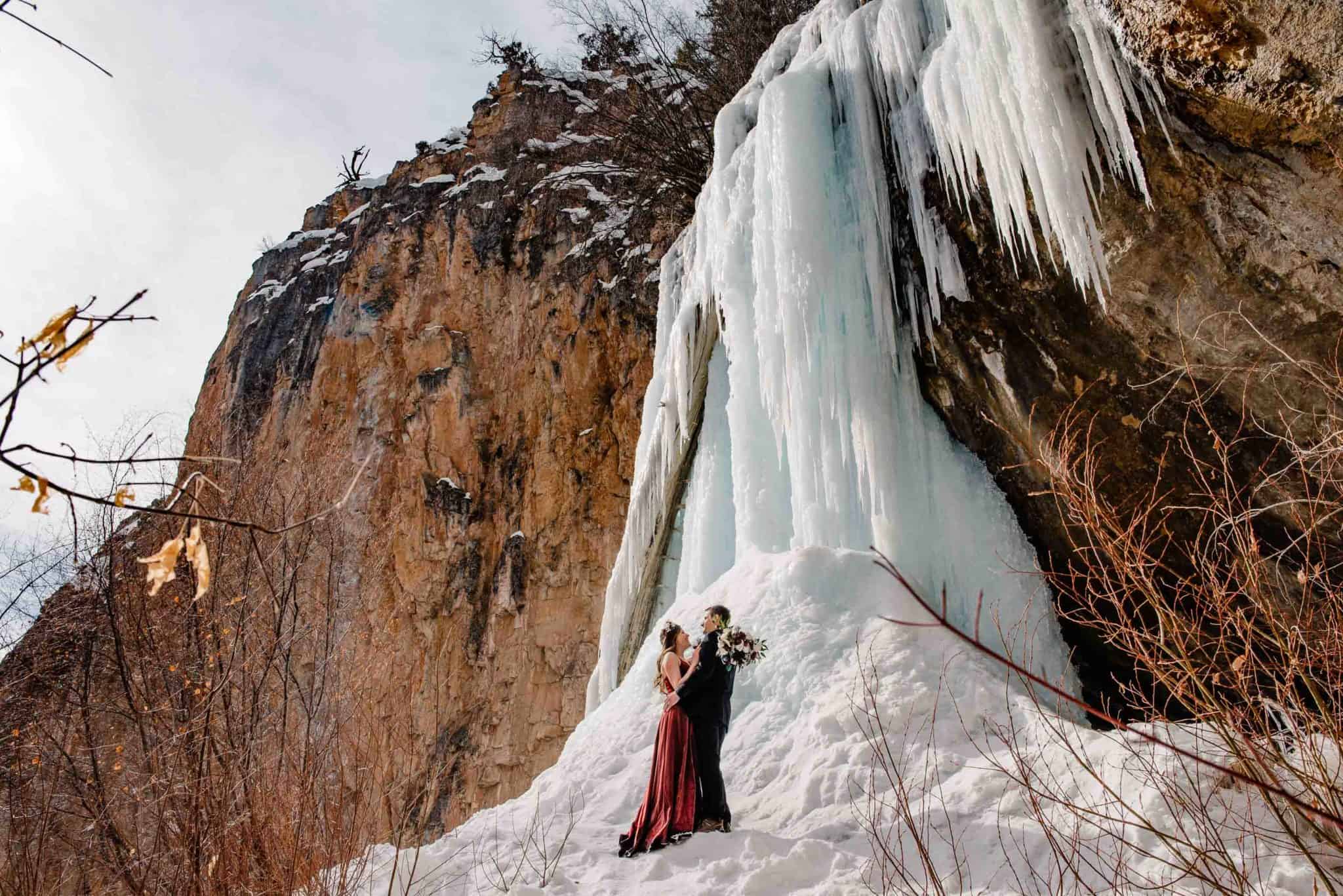 waterfall wedding venue in Colorado couple standing in front of iced waterfall