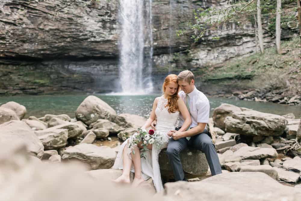 couple sitting on a rock in front of a waterfall having a waterfall wedding in Georgia photo by Jessica Kovach Photography