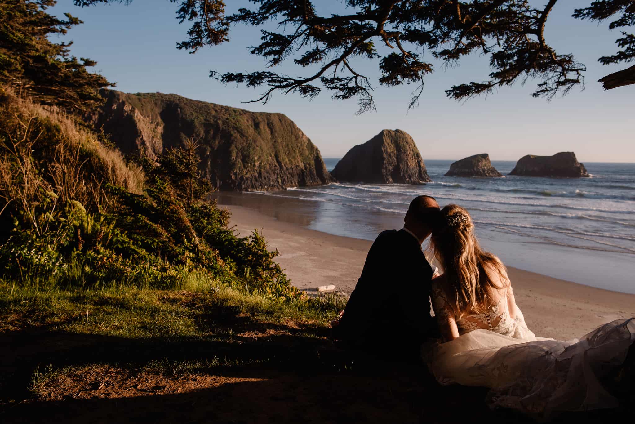 couple sitting next to each other over looking on the coast of Oregon as their Oregon elopement photographer takes their picture