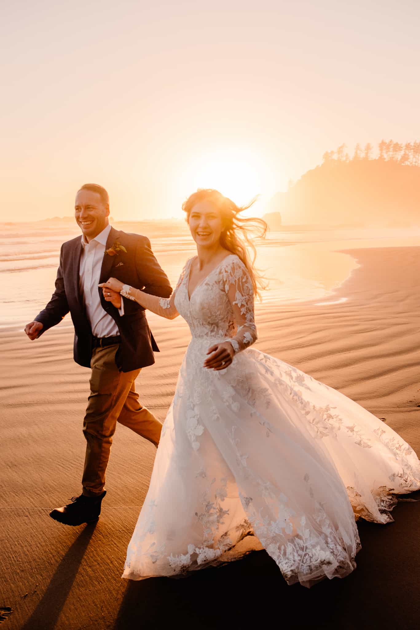 couple running on beach with orange sunset behind them as their Hawaii elopement photographer takes their photo