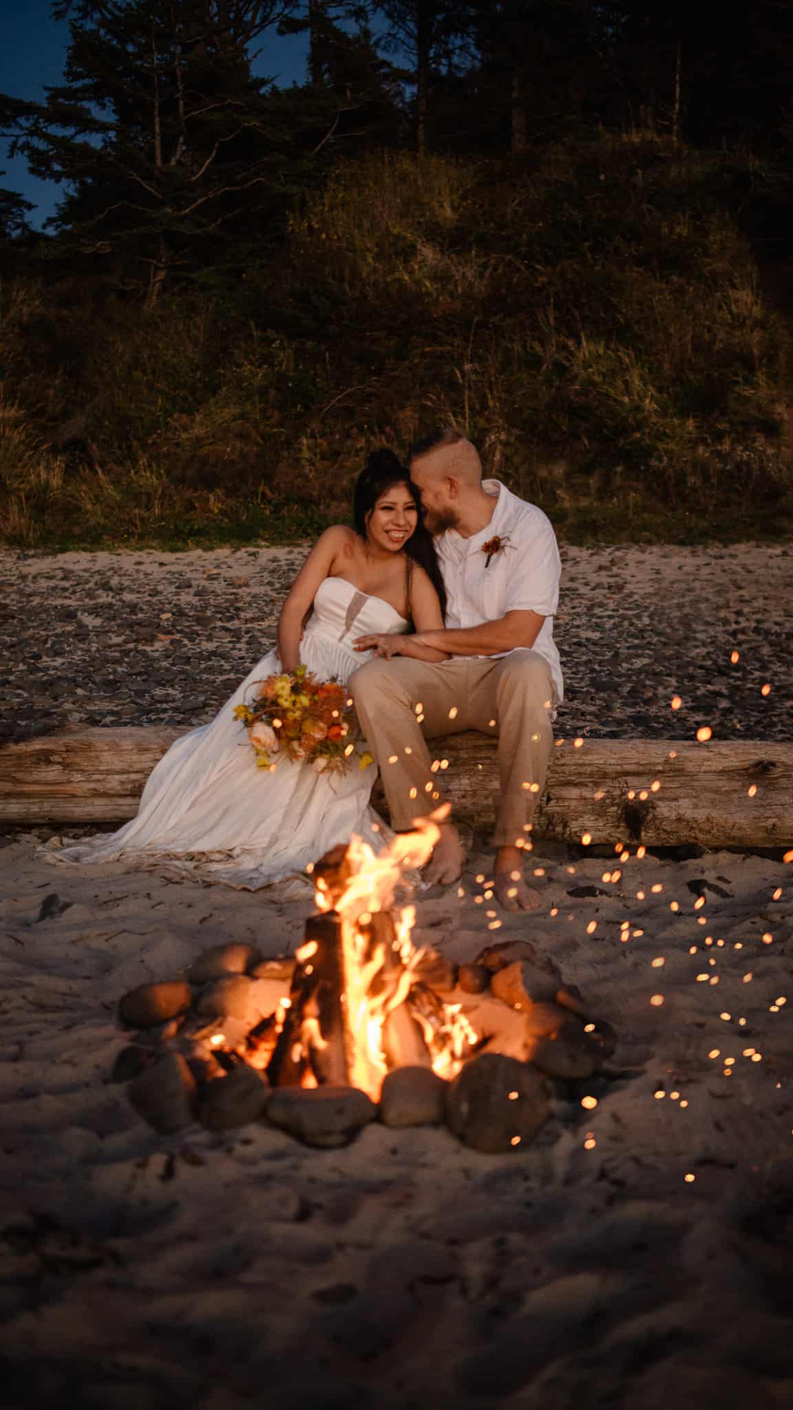 couple sitting before a beach fire as their Hawaii elopement photographer takes their photo