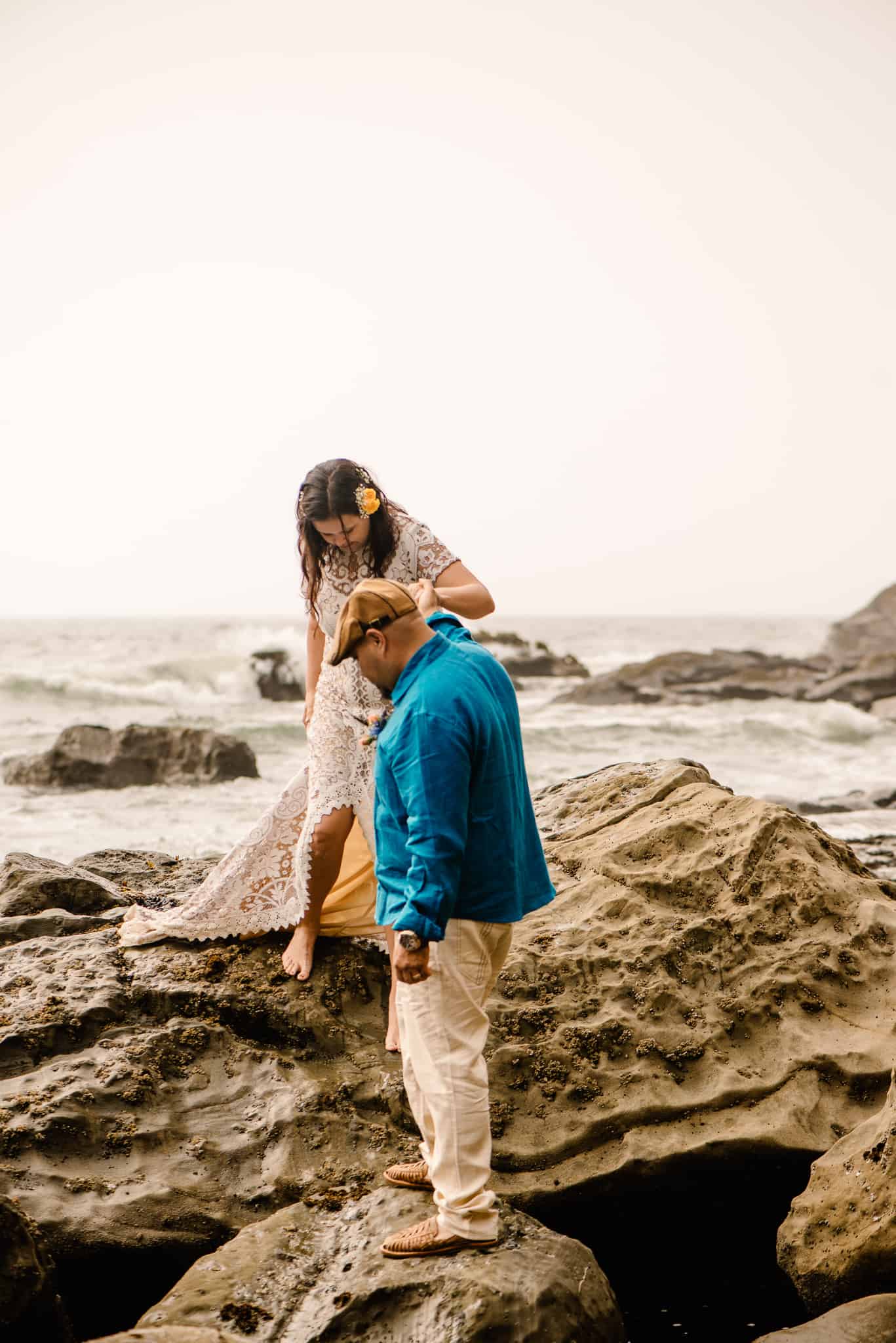 groom helping bride step down a rock as their Hawaii elopement photographer takes their photo