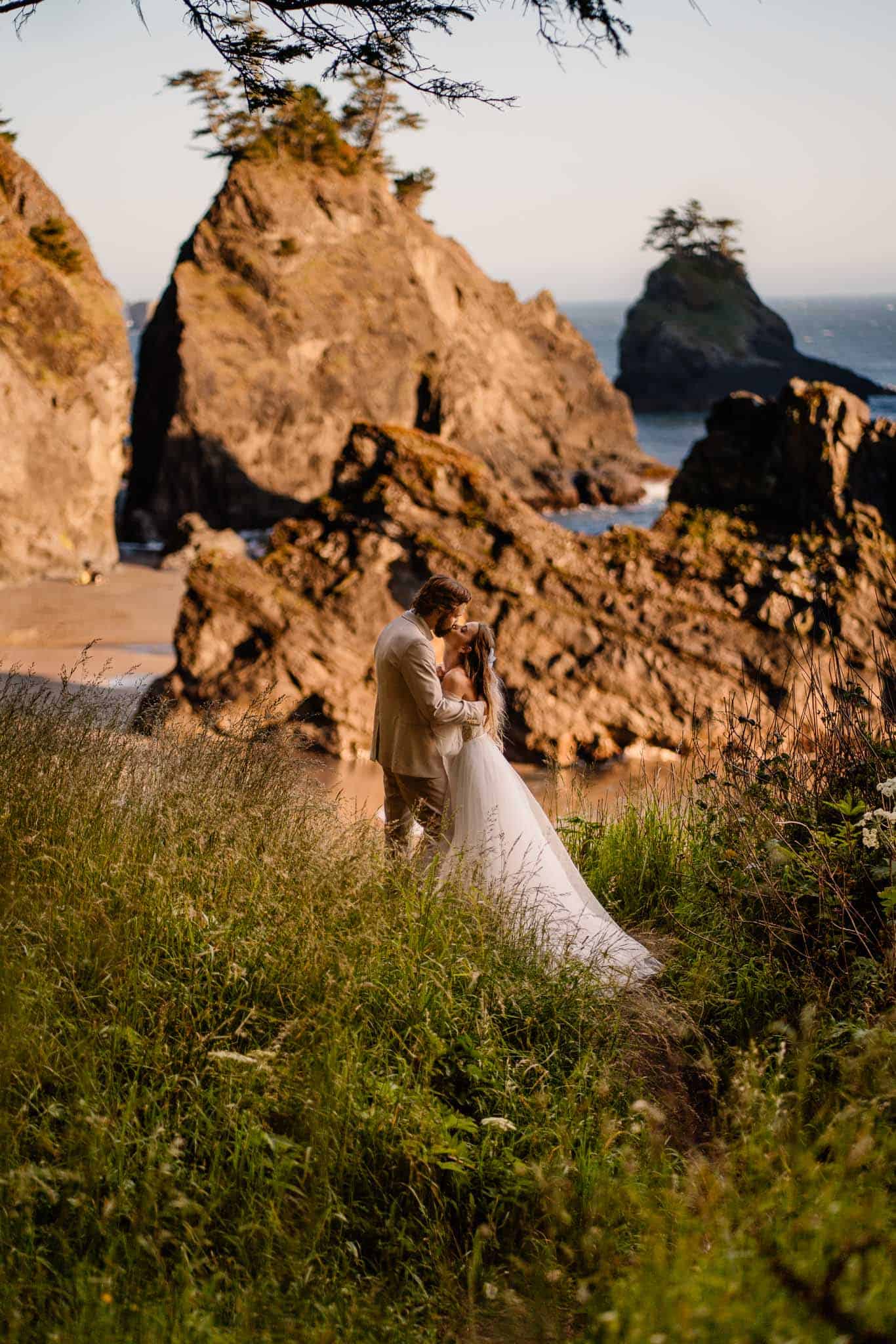 eloping couple standing on cliff edge with sea rocks behind them making this the ultimate Oregon elopement location
