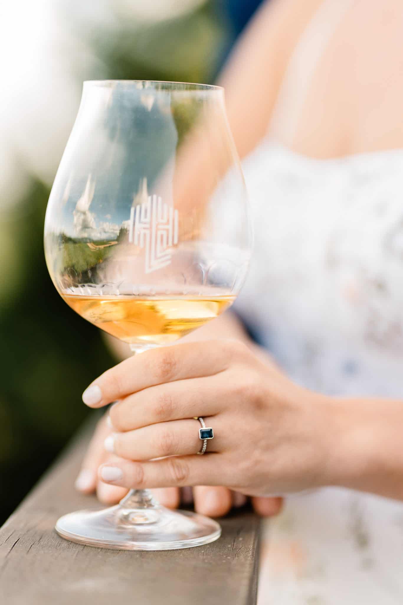 Bride enjoys chardonnay as her glass reflects the landscape of one of the best places to elope in Oregon