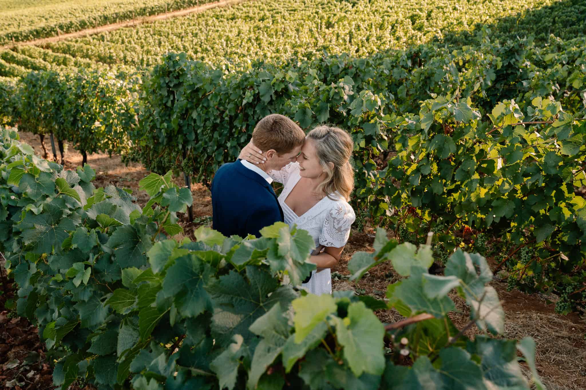 Couple embraces in a row of grape vines after exchanging vows in their favorite Oregon elopement locations