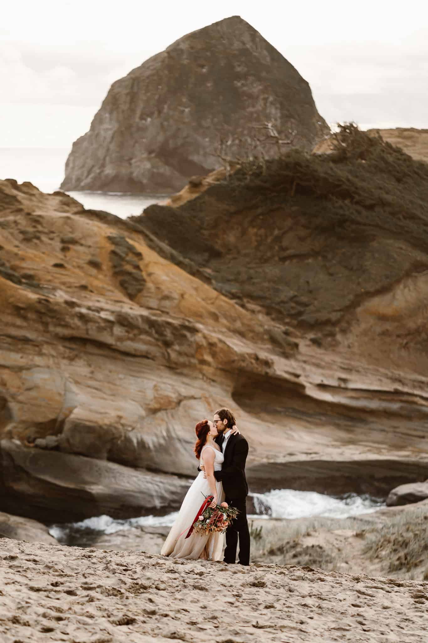 Couple embraces on reflective tide pools in their moody Oregon Coast elopement locations