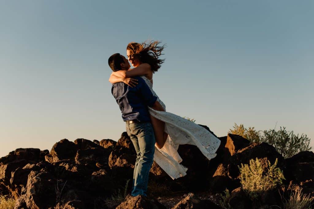 Groom twirls bride with a rocky terrain in the background while exploring this Oregon elopement location