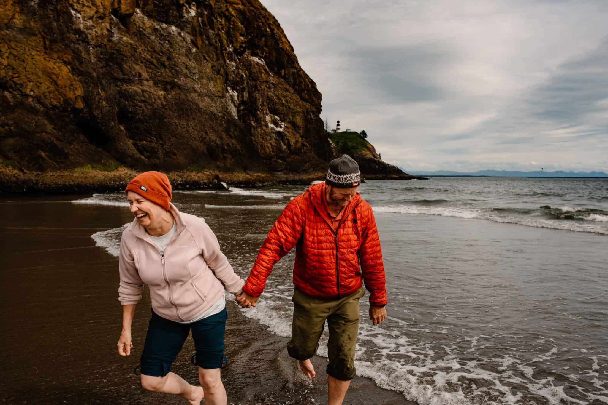 couples connection experience holding hands walking barefoot in the ocean with cliffs in the background