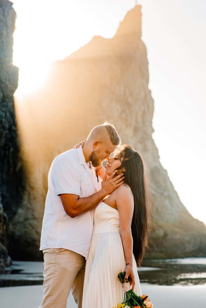 couples connection experience couple kissing in front of a sea rock with the sun peaking through the rocks