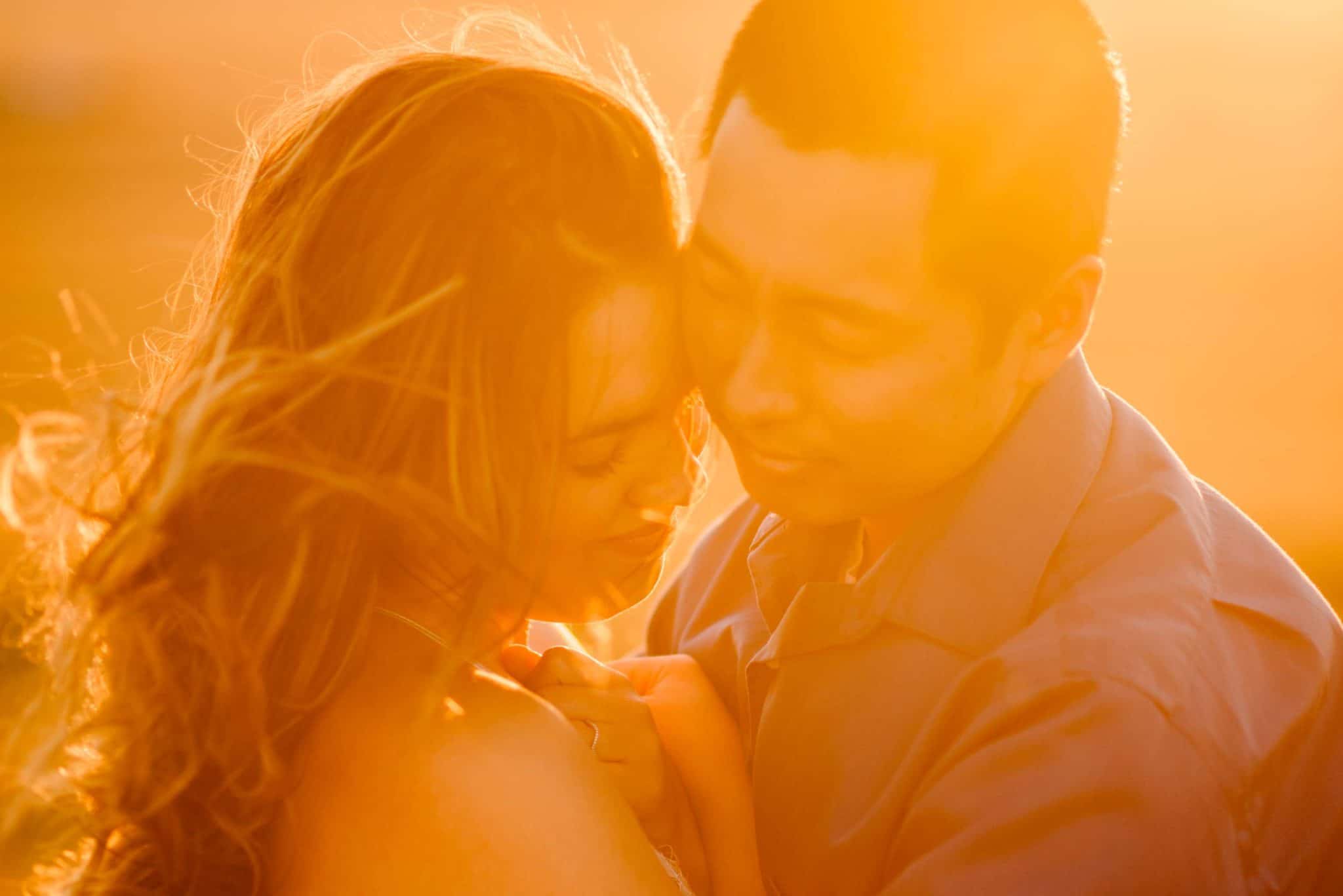 couple snuggling with sunlight breaking through illuminating them golden during a couples connection experience