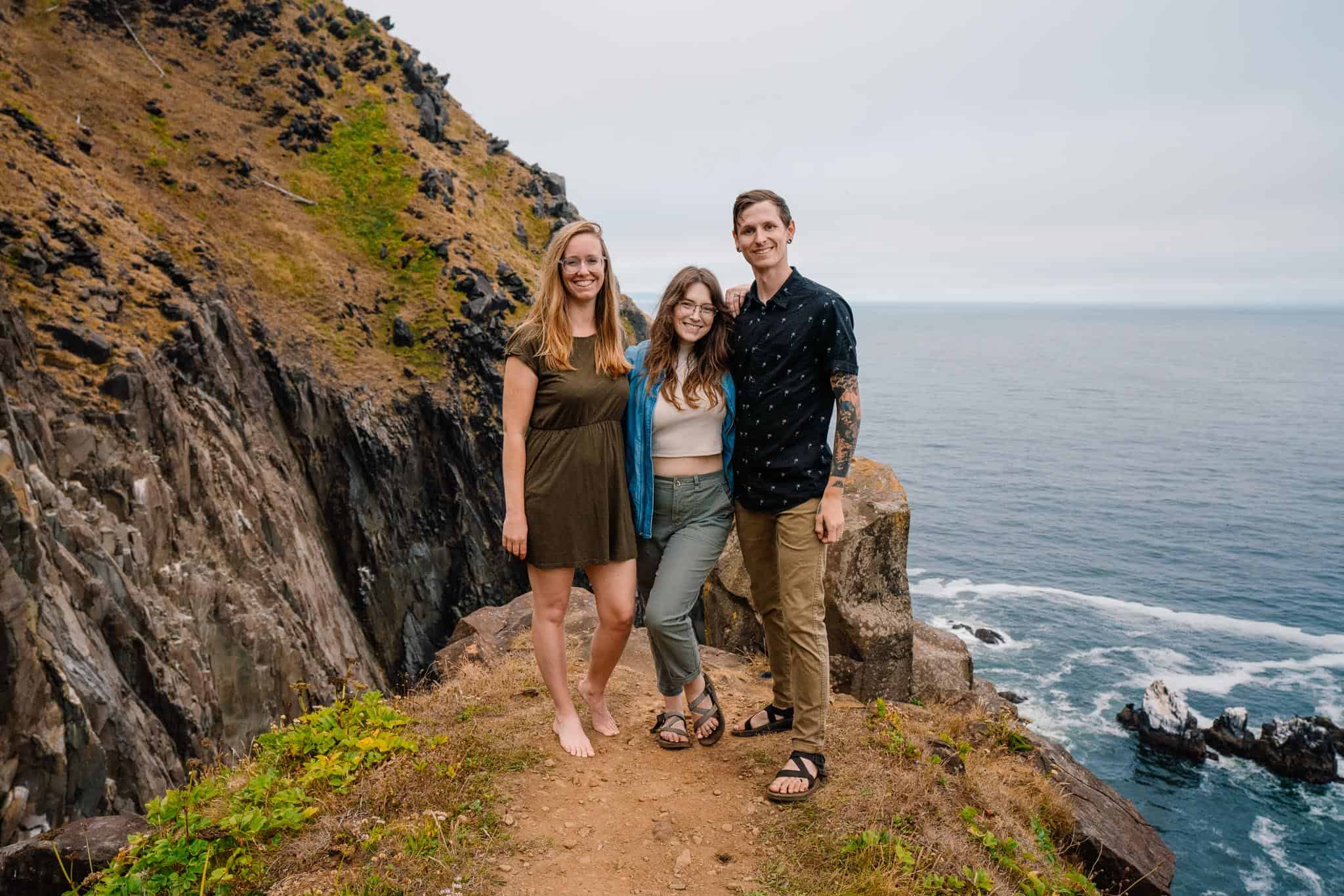On an ocean cliff side Lumalia, Sam and Kyle stand next to each other Celebrate Again and sister company The Dropped Pin
