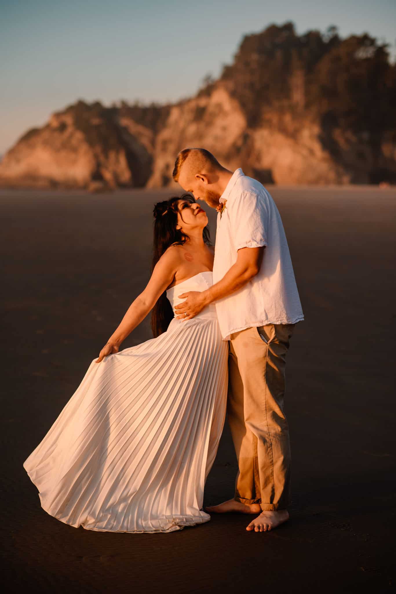couple on Oregon coast sunset hugging as light illuminates them orange for their Oregon elopement package