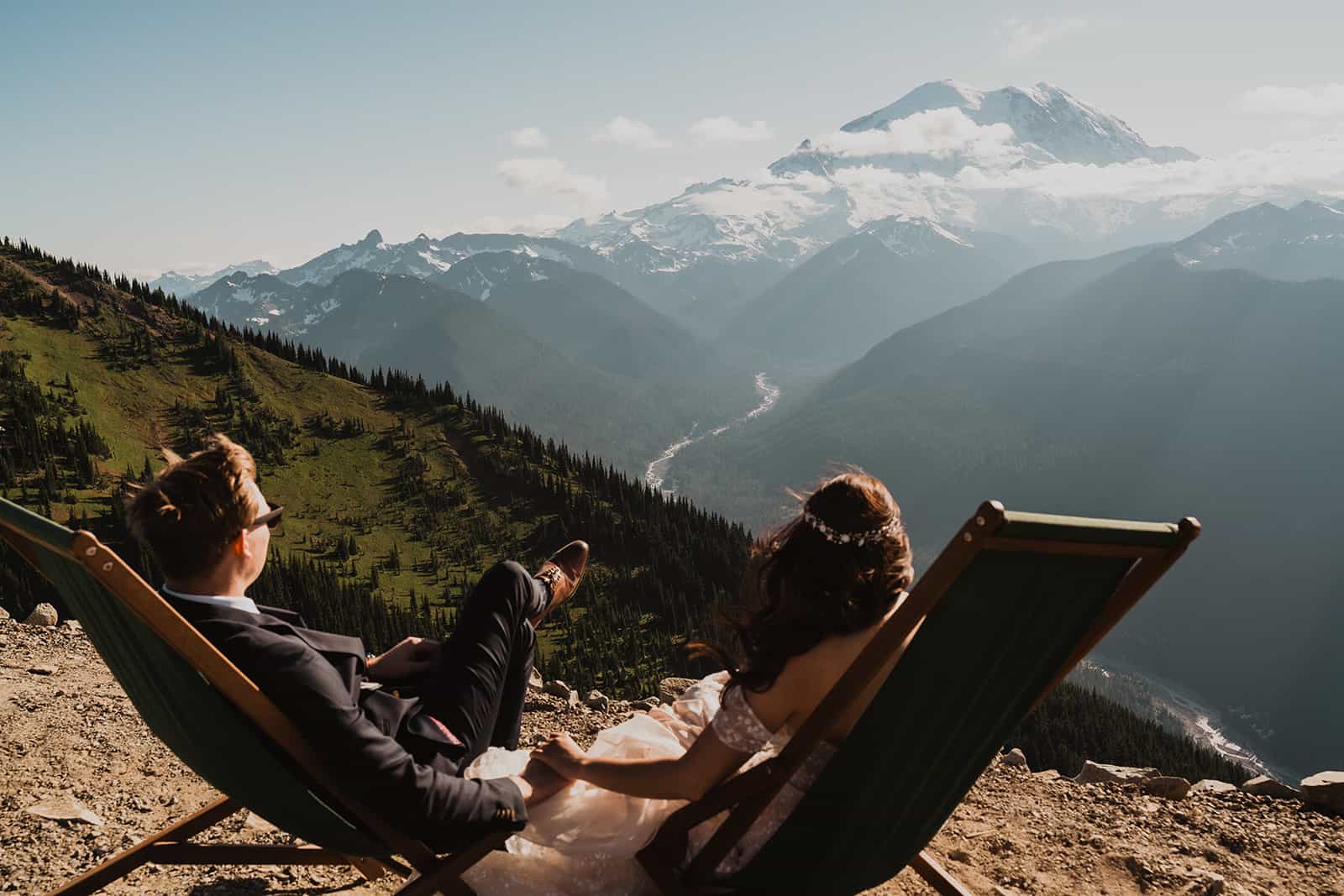 Couple in wedding attire sits in lounge chairs as they look out on Mount Rainier one of the best places to elope
