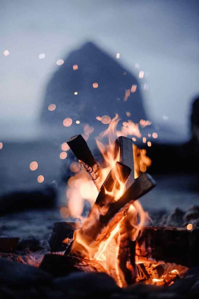 sparks flying off a fire with a sea rock in the background
