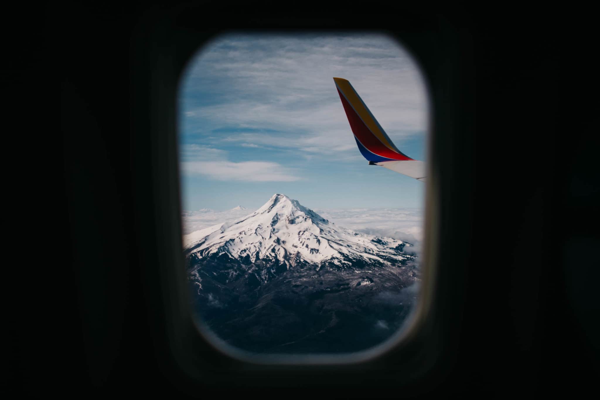 looking out a window of an airplane to a snowcapped mountain