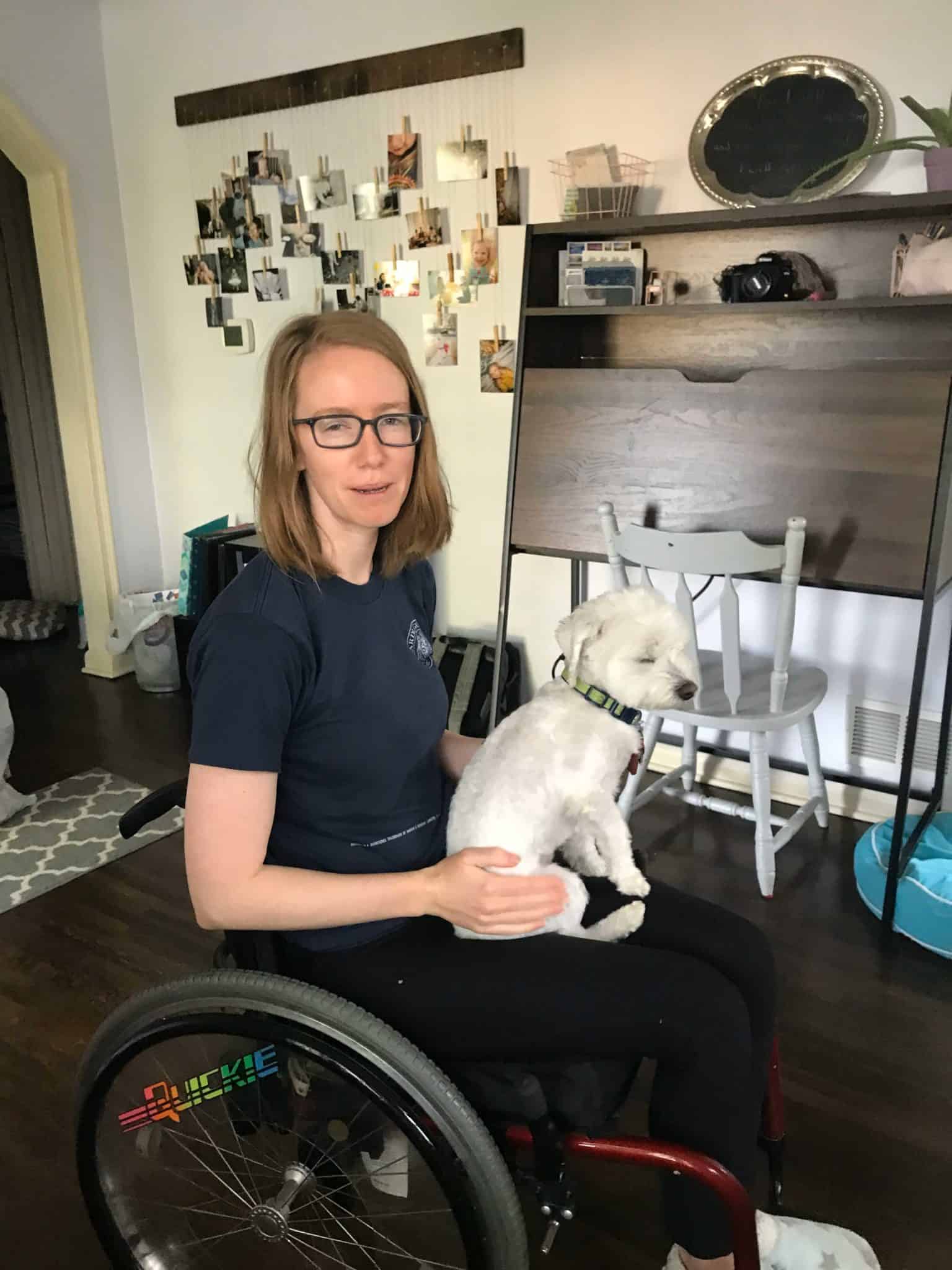 Lumalia sitting in a wheelchair when her POTS autoimmune disease was at it's worst with her dog on her lap