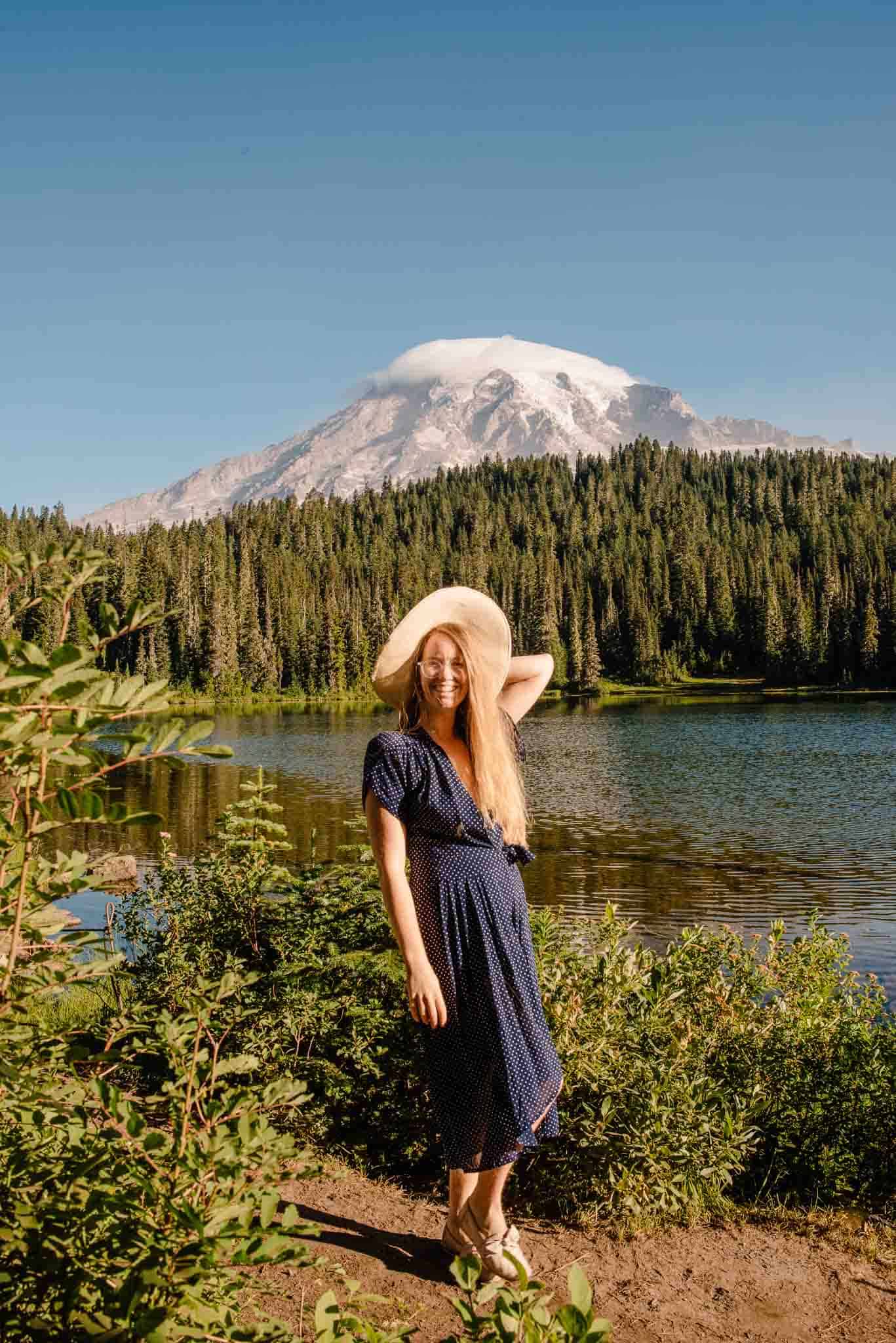 lumalia near an apline lake in a blue dress and hat