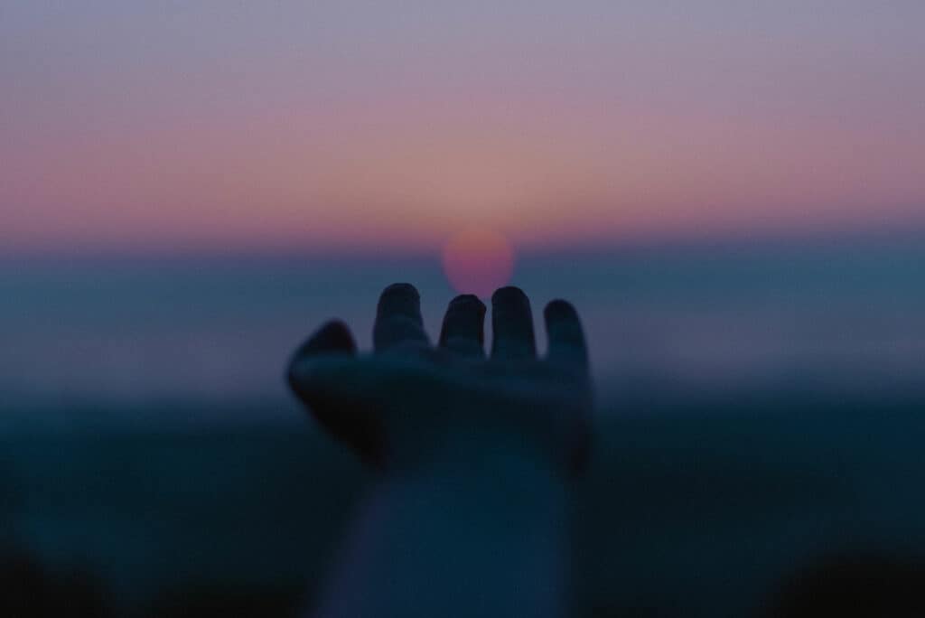 hand reaching out for sunset